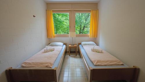 two beds in a room with a window at Delémont Youth Hostel in Delémont