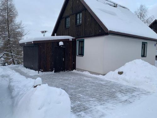 a house with a garage covered in snow at Čistá v Krkonoších - Chata Belmonda in Cerny Dul