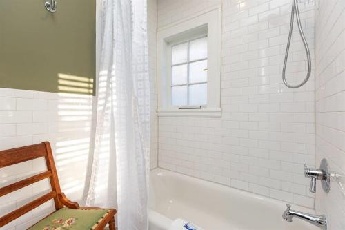ein weißes Bad mit einer Badewanne und einem Fenster in der Unterkunft Renowned historic home downtownacross from park in Winston-Salem