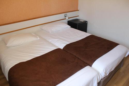 a large bed with white sheets and a brown blanket at HOTEL Chateau-Thierry Centre in Château-Thierry