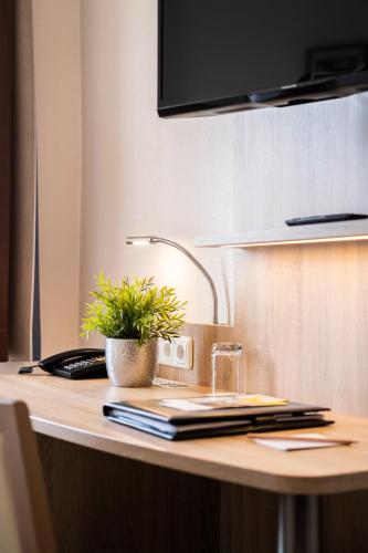 a desk with a lamp and a plant on it at Hotel Jensen in Lübeck