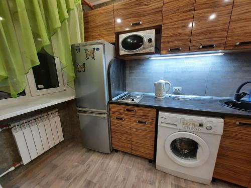 een keuken met een koelkast en een wasmachine bij Бектурова 15 in Pavlodar