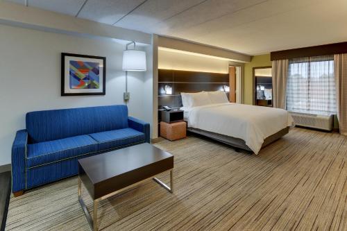 a hotel room with a bed and a blue couch at Holiday Inn Express & Suites Troy, an IHG Hotel in Troy