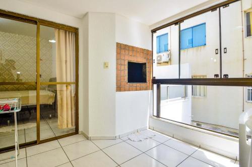 een woonkamer met een raam en een slaapkamer bij Apto a beira mar com churrasq privativa em Itapema in Meia Praia
