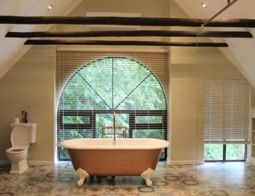 a large bathroom with a tub in front of a window at Mount Shekinah Country Hotel in Balgowan
