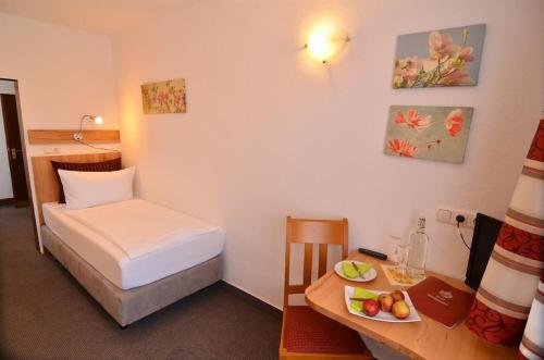 a room with a bed and a desk with a plate of fruit at Landhotel Hohmann in Hilders