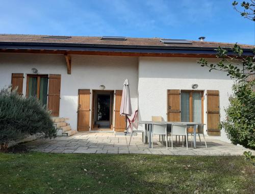 a house with a table and an umbrella on a patio at L'Aurore du Lac in Sévrier