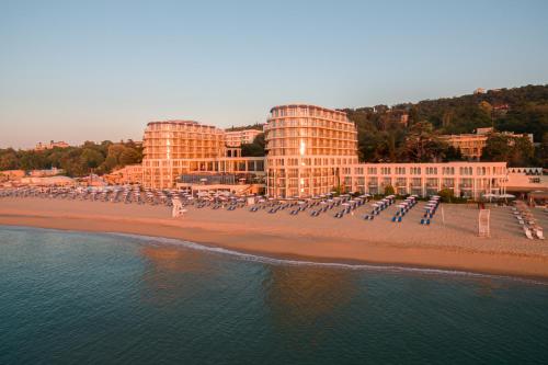 a beach with beach chairs and buildings and the water at Azalia Beach Hotel Balneo & SPA in St. St. Constantine and Helena