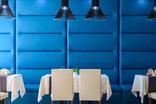 a dining room with white tables and blue wall at Azalia Beach Hotel Balneo & SPA in St. St. Constantine and Helena
