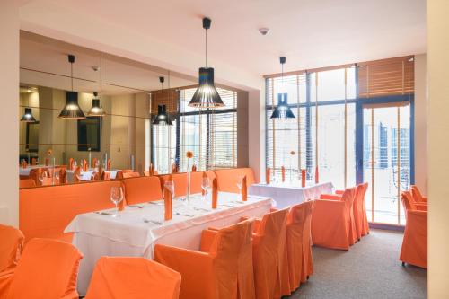 a restaurant with white tables and orange chairs at Azalia Beach Hotel Balneo & SPA in St. St. Constantine and Helena
