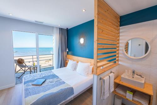um quarto com uma cama e vista para o oceano em Hôtel Café Miramar em Le Grau-du-Roi