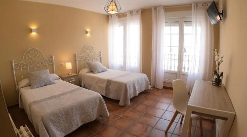 a hotel room with two beds and a table and a table at Hostal Santiago in Carrión de los Condes