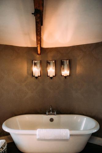 a bathroom with a tub and three lights on the wall at The Royal Hotel in Kirkby Lonsdale