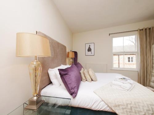 a bedroom with a bed with purple pillows and a lamp at Courtyard Cottage York - Free Parking in York