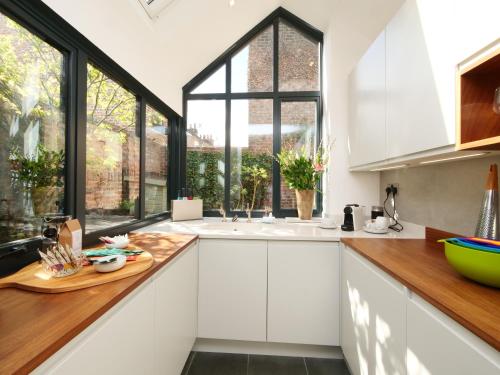 a kitchen with white cabinets and a large window at Courtyard Cottage York - Free Parking in York