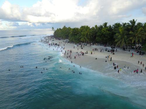 a group of people on a beach near the ocean at Shark lounge in Fuvahmulah