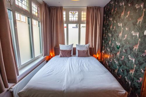 a bedroom with a bed with two pillows and two windows at Oosterhouse in Zandvoort