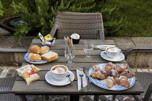 a wooden table with plates of pastries and cups of coffee at Sisters Hotel in Piano di Sorrento