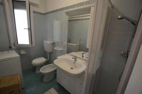 ein Bad mit einem Waschbecken, einem WC und einer Dusche in der Unterkunft Lignano Pineta nice flat in Lignano Sabbiadoro