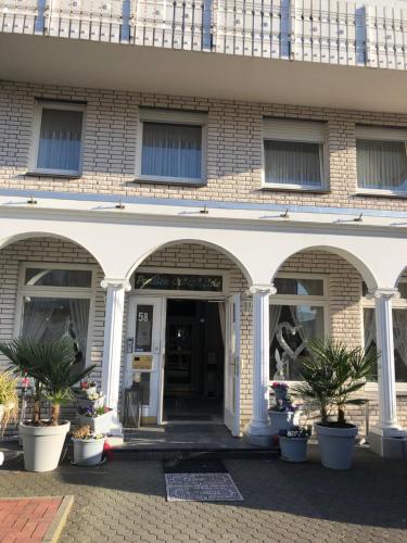 a building with arches and potted plants in front of it at Pension Ottenheide in Schloß Holte-Stukenbrock