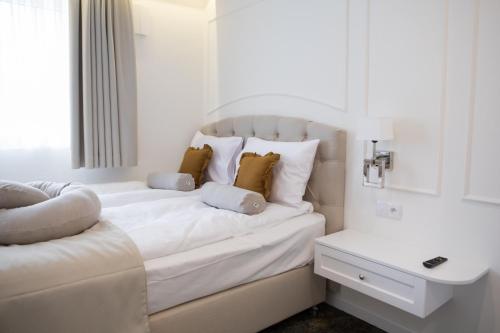 a white bedroom with a white bed with a window at Mały Sopot Boutique in Iława
