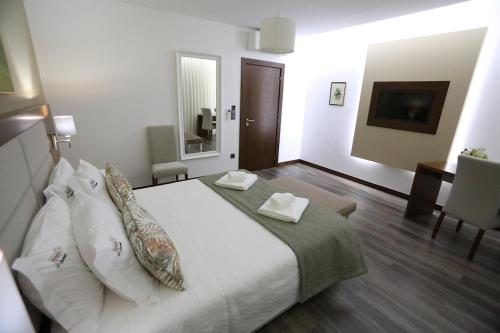een slaapkamer met een groot bed met witte lakens en kussens bij O Casario in Mirandela