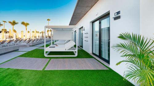 a patio with a white bench on the grass at Club Maspalomas Suites & Spa - Adults Only in Maspalomas