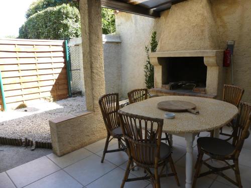 un patio avec une table, des chaises et une cheminée dans l'établissement Rez de jardin au calme et proche mer, à Mandelieu-la-Napoule