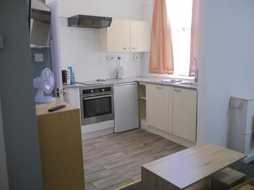 a small kitchen with white appliances and a wooden floor at Blackpool Beach Holiday Flats in Blackpool