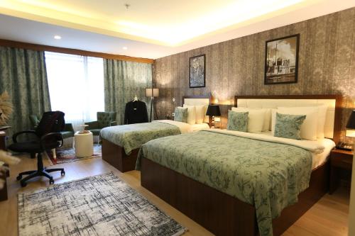 a hotel room with two beds and a desk at Cebeci Grand Hotel in Trabzon
