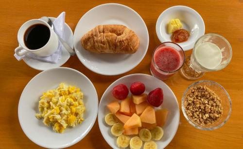 a table with plates of breakfast foods and a cup of coffee at Hostería Paraíso in Vilcabamba