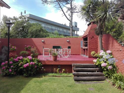 un jardín con sillas y flores en un edificio en Posada de la Villa en Villa Gesell