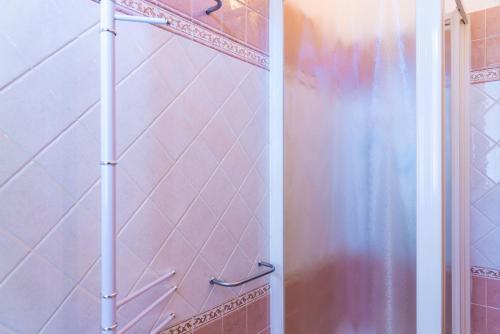 bagno con doccia e piastrelle rosa di Appartamento Passeggiata Al Mare a Campo nell'Elba