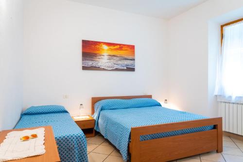 Appartamento Passeggiata Al Mare في كامبو نيل إلبا: غرفة نوم بسريرين وصورة على الحائط