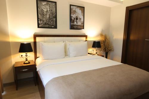a bedroom with a large white bed with two lamps at Cebeci Grand Hotel in Trabzon