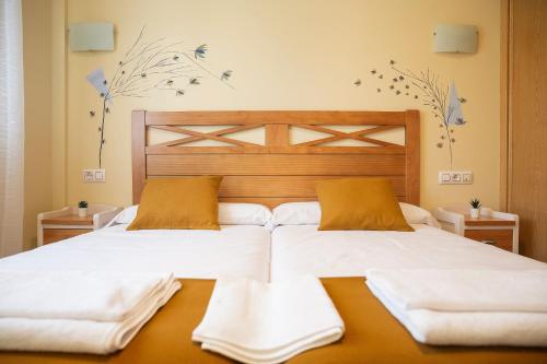 1 dormitorio con 1 cama blanca grande y 2 almohadas en HOSTAL LA GRANJA **, en Palazuelos de Eresma