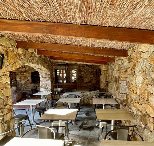 a restaurant with tables and chairs in a stone wall at Hôtel Casa Rossa & Spa in LʼÎle-Rousse
