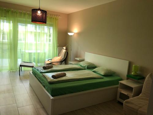 a bedroom with a bed and a chair and a window at Tóparti Wellness Apartman Delux in Velence