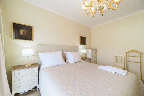 a bedroom with a white bed and a chandelier at Histórical City Center Penthouse Albufeira in Albufeira