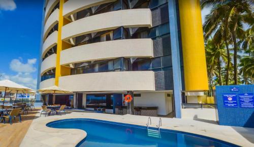 a hotel with a swimming pool in front of a building at Reymar Hotel Maceió in Maceió
