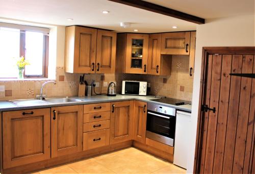 a kitchen with wooden cabinets and a sink at The Calf Cotts in Leominster