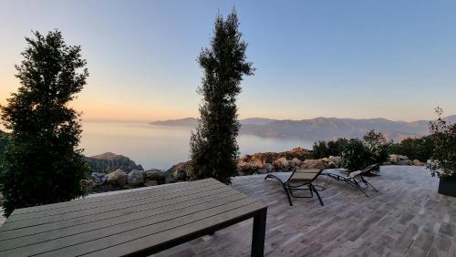 a wooden table and chairs on a patio with a view at Résidence Le Bella Vista in Piana