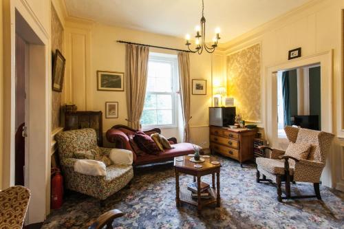a living room with a couch and chairs and a table at Family Suite, Inglewood House in Newland