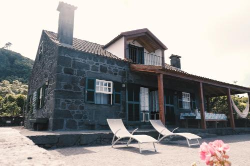 two chairs and a house with a building at Baía de Canas Villa in São Roque do Pico