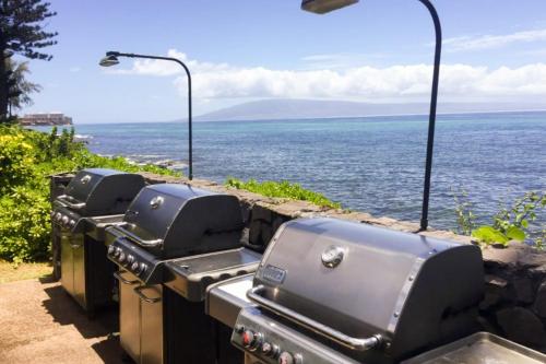 a row of old style bbq equipment on a wall near the water at Mahina Surf in Kahana