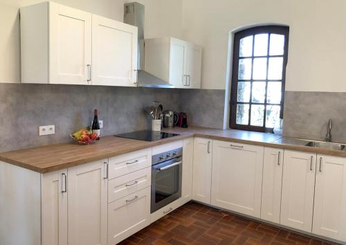 a kitchen with white cabinets and a bowl of fruit on the counter at Malepère in La Bastide-de-Bousignac