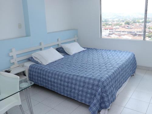 1 dormitorio con 1 cama con manta azul y ventana en Hotel Don Gregorio, en Cartago