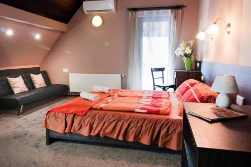 ein Schlafzimmer mit einem großen Bett und einem Sofa in der Unterkunft Emi Vendégház in Balatonszemes