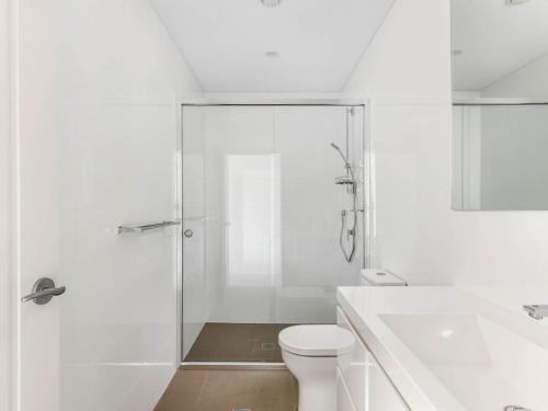 een witte badkamer met een douche en een toilet bij Sea to Believe in Gerringong
