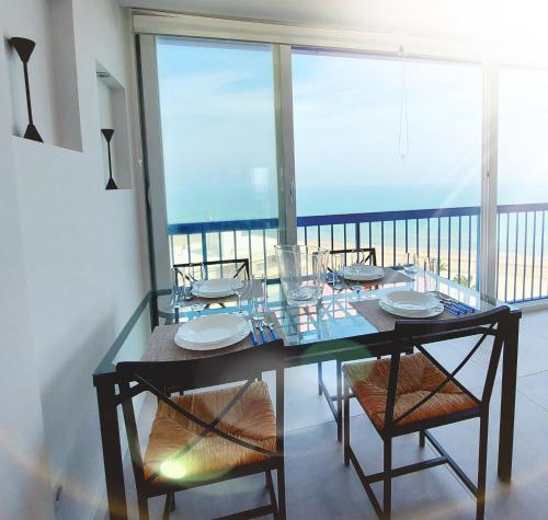 a glass dining table with chairs and a balcony at Exclusif Appartement en 1er Ligne, Vue Imprenable, Piscine, Parking Privé à Playa Mucha Vista, Alicante in El Campello